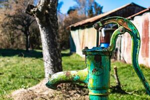 velho mão água bomba em uma bem dentro a jardim, rega e salvando água, rural ambiente foto