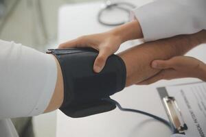 masculino médico usa uma sangue pressão monitor para Verifica a corpo pressão e pulso do a pacientes quem venha para a hospital para exames, médico tratamento e saúde Cuidado conceito. foto