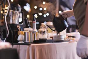 barista derramando quente água a partir de a chaleira para dentro a vidro jar. foto