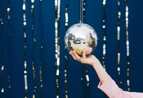 ai gerado mão do uma mulher segurando discoteca bola com fundo do fitas foto