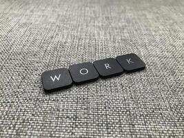 a palavra trabalhos escrito dentro Preto plástico cartas em uma cinzento fundo. foto