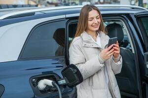 jovem o negócio mulher reabastecimento dela elétrico carro às uma ev cobrando estação. conceito do ambientalmente amigáveis veículo. elétrico carro conceito. verde viajando. foto