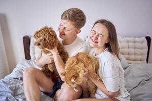 jovem casal gastos Tempo com seus animais, uma vermelho gato e uma cockapoo garota, jogando e rindo foto