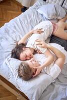 uma jovem casal é deitado em a cama, a menina é em a Rapazes ombro, concurso abraços foto