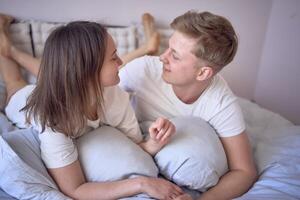 uma jovem lindo casal abraçando e se beijando dentro cama, bem estar às casa foto