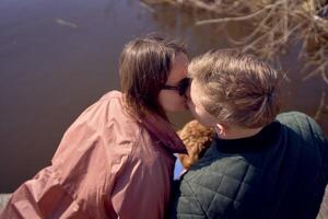 uma jovem casal com uma cachorro se beijando em a cais foto