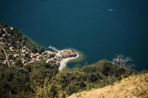 uma lindo arenoso Península em a margens do lago como com vermelho telhados do casas foto