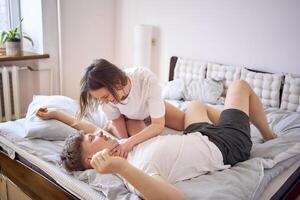 uma jovem lindo casal jogando e luta livre em a cama, minimalismo foto