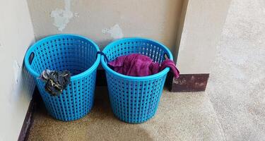 dois azul plástico cestas do usava lavanderia colocar dentro cantos do a quarto com cópia de espaço. objeto com craked concreto parede fundo. foto