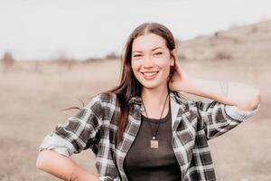 feliz jovem sorridente mulher com sardas ao ar livre retrato. suave ensolarado cores. ao ar livre fechar-se retrato do uma jovem morena mulher e olhando para a Câmera, posando contra outono natureza fundo foto