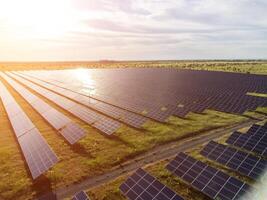 aéreo topo Visão do uma solar painéis poder plantar. fotovoltaico solar painéis às nascer do sol e pôr do sol dentro campo a partir de acima. moderno tecnologia, clima Cuidado, terra salvando, renovável energia conceito. foto