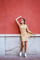à moda mulher com elevado braço inclinado em parede em rua foto