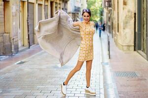 à moda jovem mulher em pé em rua e segurando grandes casaco dentro Cidade foto