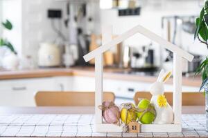 chave e minúsculo casa do acolhedor casa com Páscoa decoração com Coelho e ovos em mesa do cozinha. prédio, projeto, projeto, comovente para Novo casa, hipoteca, seguro, renda e compra real Estado foto