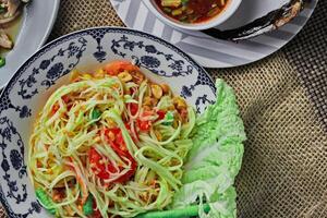 delicioso tailandês Comida em a mesa dentro uma restaurante dentro tailândia, mamão salada, larbo, cachoeira, pegajoso arroz. topo visualizar, disposição, flatlay foto