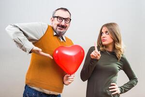 nerd homem quer para dar coração forma balão para uma lindo mulher para mostrar dela dele amor, mas ela é não interessado. foto