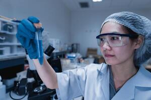 ásia cientista trabalhando dentro a laboratório, pesquisadores estão pesquisa para encontrar a resultados do a experimento, médicos estão teste sangues para evita e destruir Novo Deformação do a coronavírus através microscopia. foto