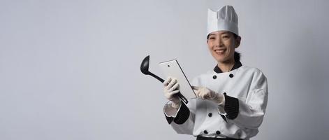 chef mulher asiática segurando um smartphone ou tablet digital e recebendo pedido on-line foto