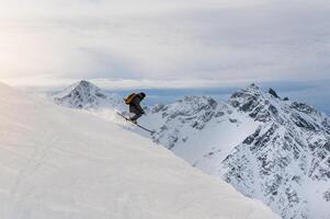 pulando esquiador. uma jovem cara saltos em uma montanha declive, descida às uma esqui recorrer foto