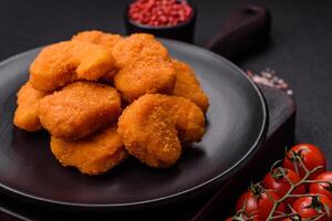 deliciosos nuggets de frango crocantes frescos em um fundo escuro de concreto foto