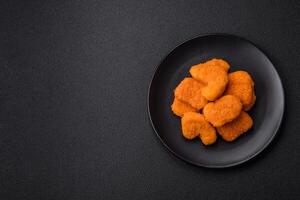 deliciosos nuggets de frango crocantes frescos em um fundo escuro de concreto foto