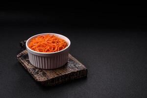 saborosa cenoura coreana picante com especiarias e ervas em um fundo escuro de concreto foto