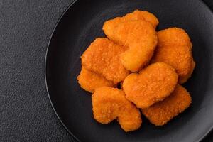 deliciosos nuggets de frango crocantes frescos em um fundo escuro de concreto foto