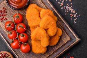 deliciosos nuggets de frango crocantes frescos em um fundo escuro de concreto foto