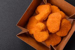 deliciosos nuggets de frango crocantes frescos em um fundo escuro de concreto foto