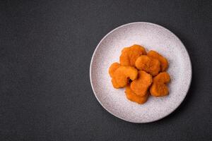 deliciosos nuggets de frango crocantes frescos em um fundo escuro de concreto foto