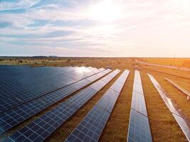 aéreo topo Visão do uma solar painéis poder plantar. fotovoltaico solar painéis às nascer do sol e pôr do sol dentro campo a partir de acima. moderno tecnologia, clima Cuidado, terra salvando, renovável energia conceito. foto