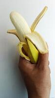 mão segurando uma amarelo banana em uma branco fundo foto