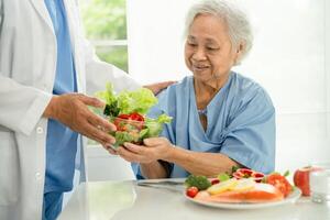 ásia idosos mulher paciente comendo salmão bife café da manhã com vegetal saudável Comida dentro hospital. foto