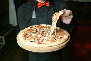 homem dentro avental segurando pizza foto