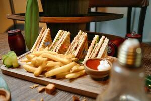 de madeira corte borda com sanduíches e francês fritas foto