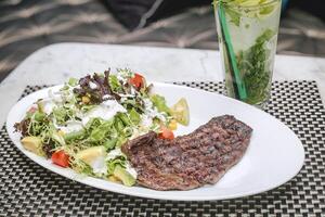 branco prato com bife e salada foto