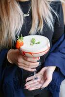 mulher segurando martini vidro com morango guarnição, enfeite, adorno foto