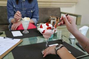 dois mulheres desfrutando gelo creme sundaes às uma mesa foto