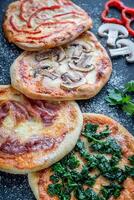 mini pizzas com várias coberturas na placa de madeira foto