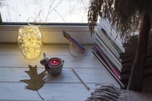 acolhedor Área de Trabalho com livros, vela luz e lindo decorações. foto