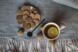 uma copo do chá com limão e bolos. hygge plano deitar. foto