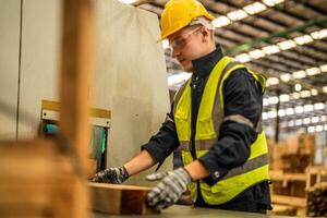 homem limpeza madeira madeira dentro Sombrio armazém indústria. equipe trabalhador carpinteiro vestindo segurança uniforme e Difícil chapéu trabalhando e verificação a qualidade do de madeira produtos às oficina fabricação. foto