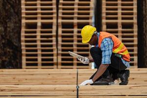 africano trabalhadores homem Engenharia caminhando e inspecionando com trabalhando suíte vestir e mão luva dentro madeira madeira armazém. conceito do inteligente indústria trabalhador operativo. madeira fábricas produzir madeira palato. foto