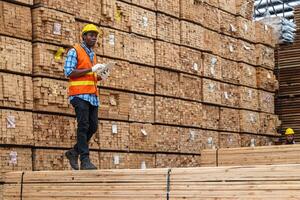 africano trabalhadores homem Engenharia caminhando e inspecionando com trabalhando suíte vestir e mão luva dentro madeira madeira armazém. conceito do inteligente indústria trabalhador operativo. madeira fábricas produzir madeira palato. foto