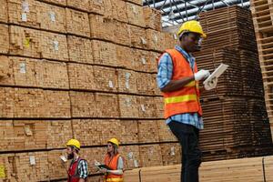 africano trabalhadores homem Engenharia caminhando e inspecionando com trabalhando suíte vestir e mão luva dentro madeira madeira armazém. conceito do inteligente indústria trabalhador operativo. madeira fábricas produzir madeira palato. foto