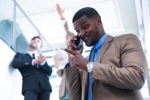 inteligente Preto homem de negocios assistindo Móvel telefone. Careca adulto homem vestindo formal vestir. pensativo afro-americano homem de negocios dentro uma perfeitamente sob medida terno em pé dentro escada dentro escritório. foto