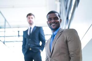 o negócio pessoas e escritório conceito. feliz sorridente homem de negocios dentro Sombrio terno. retrato do sorridente meio adulto homem de negocios em pé às corporativo escritório. homem de negocios sorridente com braços cruzado dentro escritório. foto