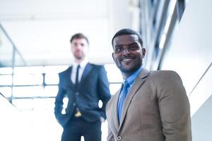 o negócio pessoas e escritório conceito. feliz sorridente homem de negocios dentro Sombrio terno. retrato do sorridente meio adulto homem de negocios em pé às corporativo escritório. homem de negocios sorridente com braços cruzado dentro escritório. foto