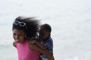 misturado raça africano e ásia mãe e Garoto é jogando às a ao ar livre área. sorridente feliz família ter Diversão corrida em a de praia. retrato do mãe e criança estilo de vida com uma único Penteado. foto