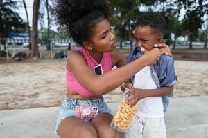 misturado raça africano e ásia mãe e Garoto é jogando às a ao ar livre área. sorridente feliz família ter Diversão corrida em a de praia. retrato do mãe e criança estilo de vida com uma único Penteado. foto